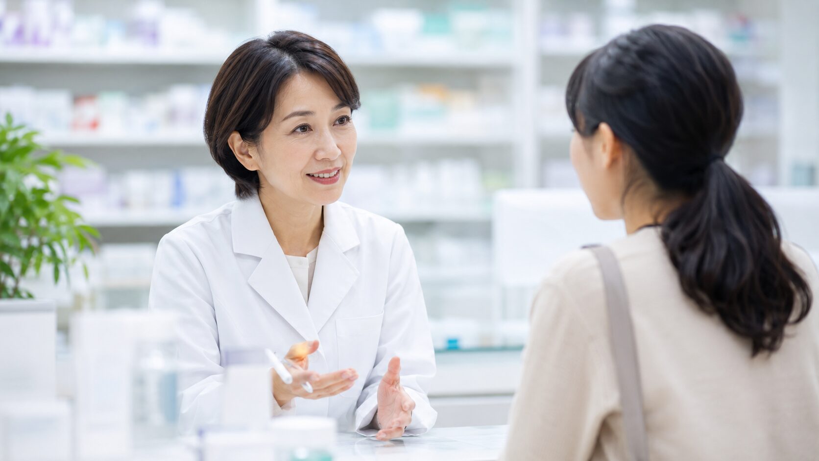 便秘や薬の不安について薬局で薬剤師に相談する女性