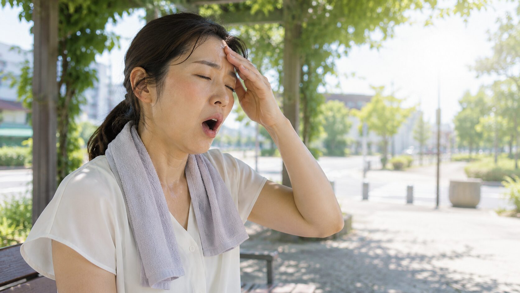 暑い公園であくびとめまいを感じる日本人女性